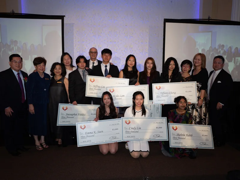 CAAF board members photographed with the Asian American Youth Scholarship winners holding their award checks.