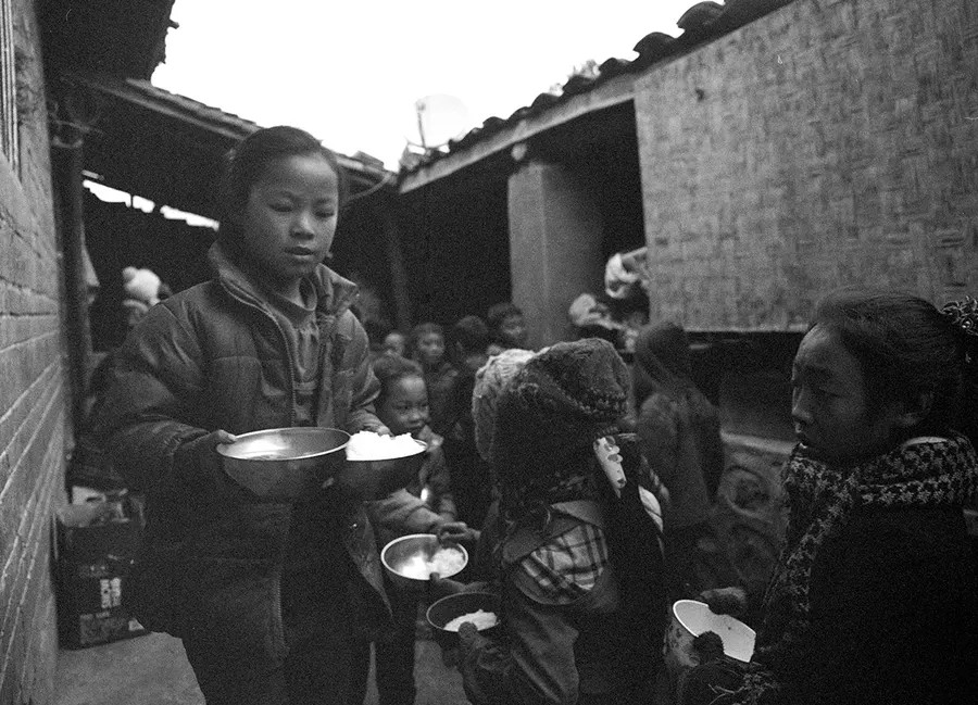 Children queuing with bowls for a meal, Liangshan Prefecture.